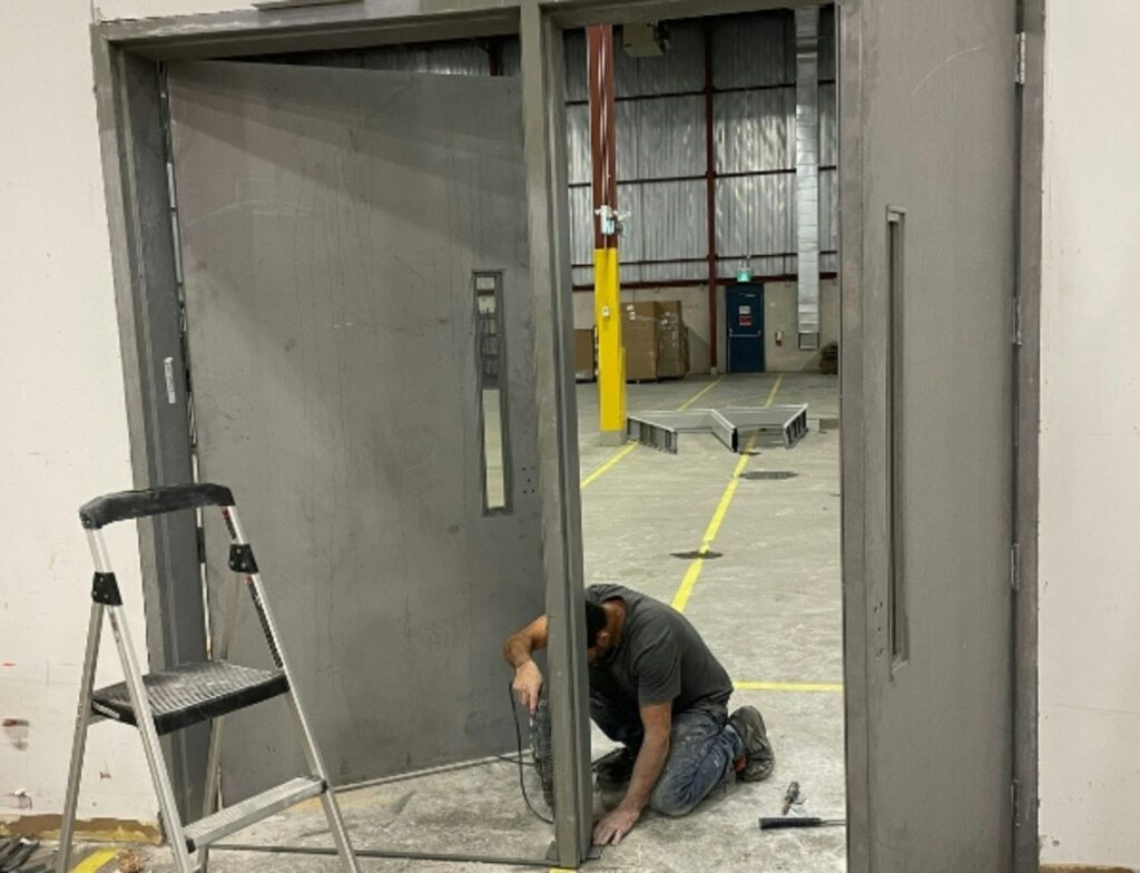 A man kneeling down next to a metal door